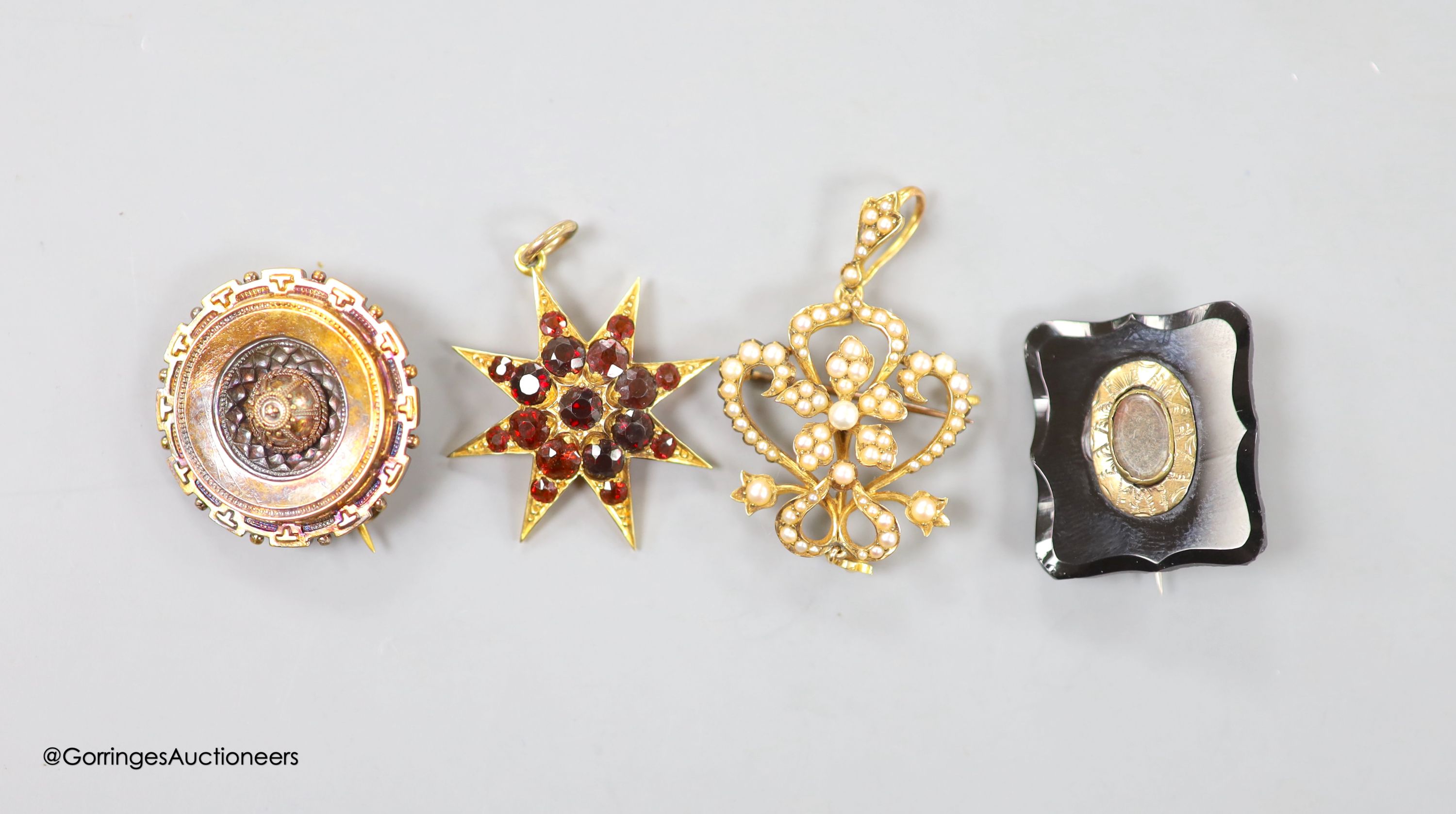 An Edwardian 15ct and seed pearl set drop pendant brooch, overall 48mm, gross 6.4 grams, a Victorian yellow metal target brooch, gross 5 grams, a Victorian yellow metal and a similar graduated garnet set starburst brooch